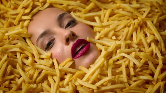 beauty-fashion-model-girl-lying-in-tasty-french-fries-makeup-face-in-chips.jpg